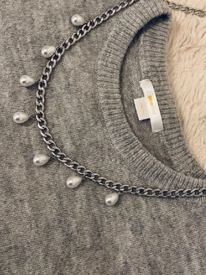 Kedjehalsband med droppformade pärlor - Snyggt halsband i silverfärgad metallkedja med droppformade vita pärlor som hänger längs hela kedjan. Perfekt för att ge din outfit en cool och trendig touch. Passar dig som gillar statement-smycken och vill sticka ut lite extra.