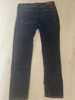 Dressman Mörkblå raka jeans  nya  - Säljer ett parDressman. Nya  mörkblå jeans med raka ben och klassisk femficksdesign. Jeansen har slitningar på benen för en cool look och en läderpatch bak i midjan. Perfekta till vardagsstilen och passar till det mesta.
