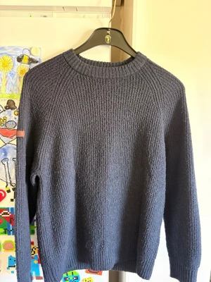 Mörkblå stickad tröja från superdry - En enkel och stilren mörkblå stickad tröja från superdry med rund hals och långa ärmar. Tröjan har ribbstickade muddar vid hals, ärmslut och nederkant. Perfekt för lager på lager och passar till det mesta i garderoben.