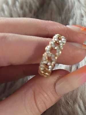 Guldfärgad ring med pärldetaljer - Snygg guldfärgad ring med ett flätat mönster och små pärlliknande detaljer runt hela ringen. Ringen har en unik design som sticker ut och passar perfekt för dig som gillar accessoarer med det lilla extra.