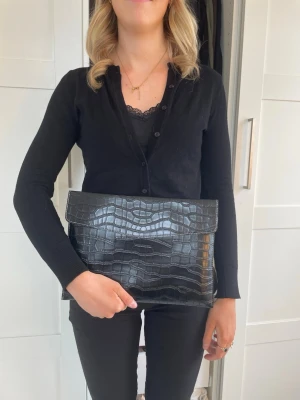 Datorfodral i krokodil mönster  - Stilrent datorfodral tillverkat av veganskt läder i vattentätt material. Fodralet stängs med knapp. Fodralet skyddar din dator effektivt samtidigt som det ger din outfit en extra touch. Storlek: 34 × 25 cm - Inifrån 33 x 24💌