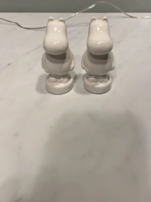 Muminfigurer i keramik, vita - Två vita muminfigurer i keramik,peppar och saltströare. Figurerna har klassisk muminform och är tillverkade i blankt material. Märkta med Moomin Characters undertill.Priset kan diskuteras.