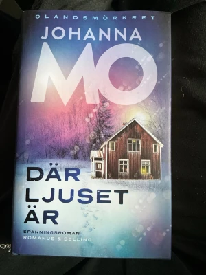 Där ljuset är av Johanna Mo - Spänningsroman av Johanna Mo, första delen i serien Ölandsmörkret. Omslaget har en vintrig känsla med ett rött trähus mot en blå och lila bakgrund. Boken handlar om två systrar som återvänder till sitt barndomshem på Öland och konfronterar familjehemligheter.
