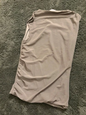 Militärgrön ärmlös topp med rynkade sidor - Säljer en grön ärmlös topp med rynkade detaljer längs sidorna. Toppen har en enkel och stilren design i ett mjukt, stretchigt material som känns skönt mot huden. Perfekt att matcha med jeans eller kjol för en clean look.