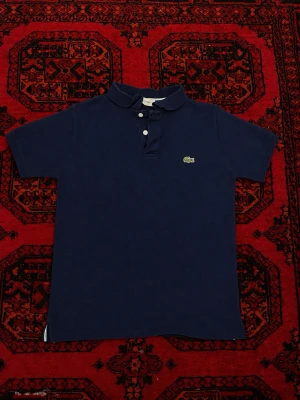 Marinblå pikétröja från Lacoste - Pikétröja från Lacoste, Skick 10/10 har använts fåtal gånger. Piken är i storlek EU S och Längden på piken ligger på 63 cm. Pris går att diskutera vid bundle köp / snabbaffär 💯