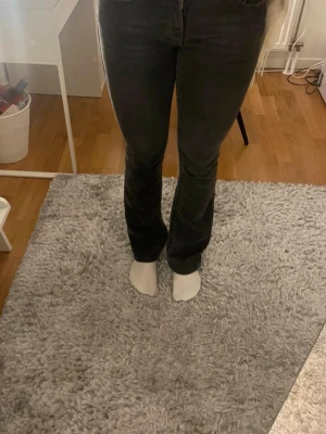 Svarta bootcut jeans med hög midja - Snygga svarta bootcut jeans med hög midja och klassisk femficksdesign. Jeansen har en lätt utsvängd passform nertill och är perfekta för en trendig look. Materialet är denim med lite stretch för extra komfort.