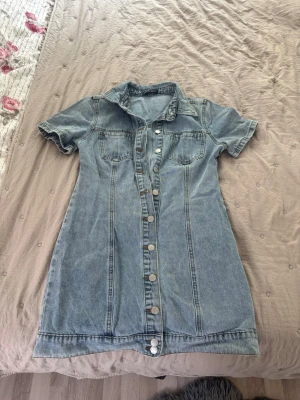 Jeansklänning med knappar från SHEIN - Snygg jeansklänning från SHEIN i ljusblå denim med korta ärmar och knappar hela vägen framtill. Klänningen har två bröstfickor och klassisk krage, perfekt för en trendig och avslappnad look.🩵