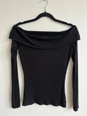 Svart ribbad offshoulder topp - Svart ribbad topp med offshoulder-design och långa ärmar.