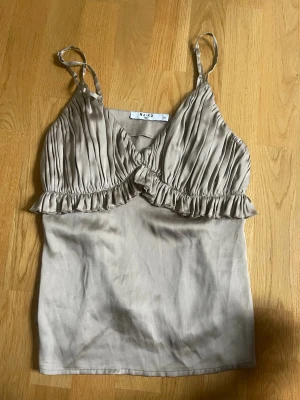 Satin linne från NA-KD - Säljer denna satin topp från NA-KD i champagne färg, super fin men passar tyvärr inte mig så säljer vidare🙌.