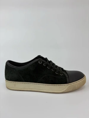 Svarta Lanvin sneakers med mocka och gummitå - Stilrena svarta sneakers med ovandel i mocka och tåparti i svart gummi. Skorna har svarta skosnören och en beige sula med klassisk design. Perfekta för dig som gillar en clean och tidlös look.