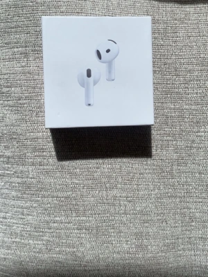 Airpods 4  - Säljer ett par vita Apple AirPods med tillhörande laddningsetui. Trådlösa in-ear-hörlurar med stilren design och smidig förvaring i det kompakta etuiet. Perfekta för musik, samtal och vardagsbruk. Hörlurarna har brusreducering 
