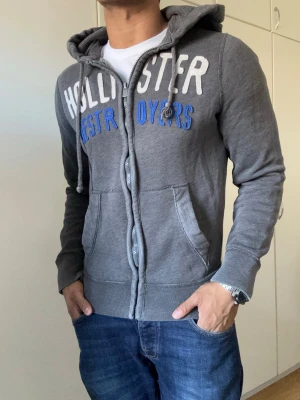 Vintage Hollister Zip-Hoodie - Säljer denna riktigt feta hollister koftan | Storlek S | mycket bra skick förutom litet hål vid vänster armhåla (se sista bild) syns knappast | Modell 175cm, 69kg | Längd≈61cm, bredd armhåla- armhåla ≈ 51cm