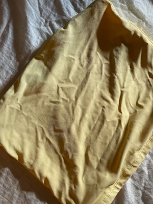 Ljusgul tubtopp i bomull - Säljer en ljusgul tubtopp i mjukt bomullstyg. Toppen är enkel och stilren med bandeau-modell och ärmlös design, perfekt för varma dagar eller som layering-plagg.