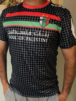Palestino fotbollströja svart mönstrad / xl  - Snygg svart fotbollströja från Palestino med prickigt mönster, röda och gröna ränder samt klubbmärke på bröstet. Texten 'Bank of Palestine' framtill och vit karta på ryggen. Röd krage och korta ärmar. Perfekt för fotboll eller träning.