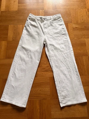 Vita raka jeans från Lindex - Säljer ett par vita jeans från Lindex med rak passform och hög midja. Jeansen har klassisk femficksdesign, knapp och dragkedja framtill. Perfekta för en clean och stilren look. Materialet är kraftigt denim i bomull.