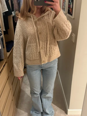 Beige stickad hoodie med knappar - Mysig beige stickad hoodie med knappar framtill och två stora fickor. Tröjan har en avslappnad passform, ribbade muddar och luva. Perfekt & såå fin till sena sommarkvällar 💕💕