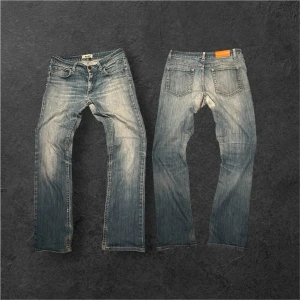Vintage Acne Studios Jeans med fet tvätt - Säljer ett par ljusblå jeans från Acne Studios med klassisk femficksmodell och snyggt slitna detaljer. Jeansen har raka ben och normal midja. Perfekta för dig som gillar en avslappnad och trendig look.