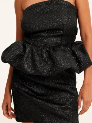 Svart axelbandslös volangklänning - Multiklänning som går att variera tex som svart axelbandslös klänning med strukturerat tyg och stor volangdetalj i midjan. Kort modell med figurnära passform och elegant struktur som ger en lyxig känsla. Perfekt för dig som vill sticka ut.