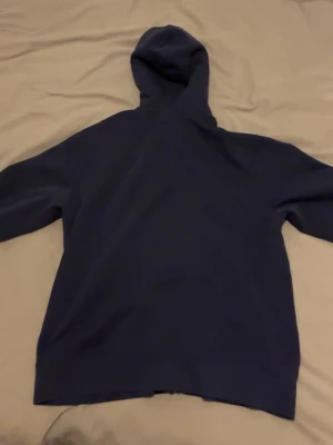 Mörkblå hoodie från Polo Ralph Lauren - Snygg mörkblå hoodie från Polo Ralph Lauren med dragkedja framtill och klassiska loggan broderad på bröstet. Hoodien har huva och långa ärmar, perfekt för en chill och stilren look. Materialet känns mjukt och bekvämt, passar till det mesta i garderoben.