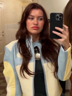 Pastellfärgad skinnjacka med dragkedja - Säljer en unik skinnjacka i pastellblått, ljusgult och vitt. Jackan har en croppad passform, hög krage och dragkedja framtill. Snygga detaljer med broderad patch på bröstet. Fickor på sidorna. Denna har varit omtyckt men behöver tyvärr rensas ut. Inte märkbart använd