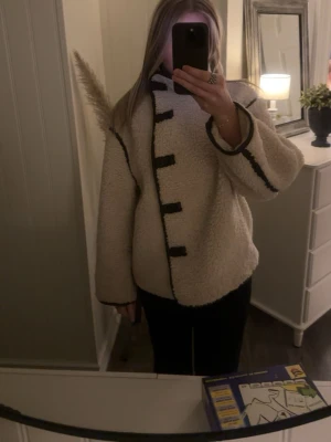 teddyjacka med svarta detaljer - Säljer en vit teddyjacka med oversized passform och svarta kontrastkanter. Från H&M.💕