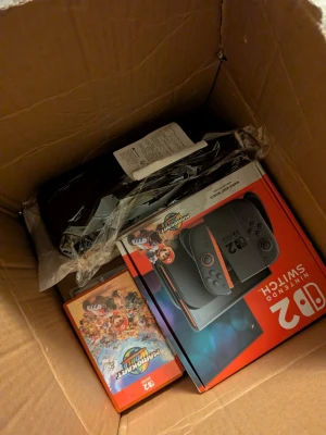 Nintendo Switch OLED Mario Edition - Nintendo Switch OLED Mario Edition med röd och svart design. Konsolen har en stor OLED-skärm och Joy-Con-kontroller i matchande färger. Medföljer gör även spelet Mario Kart 8 Deluxe. Perfekt för gaming hemma eller på språng.