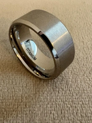 Titanium Ring 10mm bred - Borstad yta - Titanium ring med borstad finish - passar för män som gillar minimalistisk design med edge.   Material: Titanium (Titanium-stämpel) Färg: Silver   Design: Handgjord, Borstad yta, Bekväm passform, Passar för män Bredd: 10 mm   Storlek: 19,8 mm i diameter (US 10) Skick: Helt ny Frakt: Alltid snabb leverans                                      🎁 Levereras i en fin presentförpackning, en perfekt present till din pojkvän, make, pappa, bror, son, morfar samt till vänner 