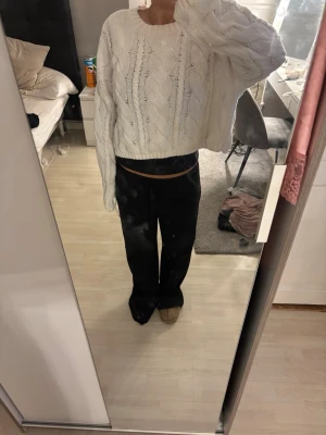 Vit kabelstickad croppad tröja - Säljer en vit kabelstickad tröja med croppad passform och rund hals. Tröjan har långa ärmar och ett snyggt flätmönster över hela plagget. Perfekt för dig som gillar en avslappnad men trendig stil.