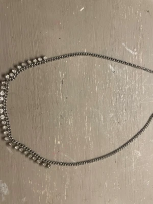 Silverfärgat halsband med pärlor - Snyggt halsband i silverfärg med små, runda pärlor längs hela kedjan. Halsbandet har en enkel och stilren design som passar perfekt till olika outfits. Materialet ser ut att vara metall och pärlorna ger en elegant touch.