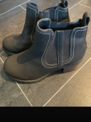 Svarta klassiska gummistövlar - Säljer ett par svarta gummistövlar med enkel och stilren design. De har rund tå och mellanhögt skaft, perfekta för regniga dagar. Tillverkade i slitstarkt gummimaterial som håller fötterna torra.