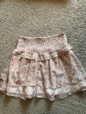 Blommig rosa vit volang kjol - Nyskick💞 super fin men säljer för att den inte passar💞 säljer en matchande tröja, se min profil om du är intresserad💞storlek 170💞 midja ca 34cm tvärs över, längd ca 40cm💞 Stretchigt material💞