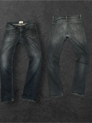  Acne Studios Jeans med sjuk tvätt - Säljer ett par mörkblå slim fit jeans från Acne Studios med snygg slitning och klassisk femficksmodell. Jeansen har dragkedjegylf, bälteshällor och är tillverkade i denim med en lätt stretch för skön passform. Perfekta för en trendig och avslappnad look.