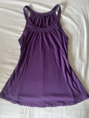 Lila  linnetopp - Säljer en lila linnetopp med racerback och rund halsringning pipeline soprtig vibe. Toppen är ärmlös och har en lös passform, perfekt för varma dagar eller träning. Materialet känns mjukt och lätt mot huden.