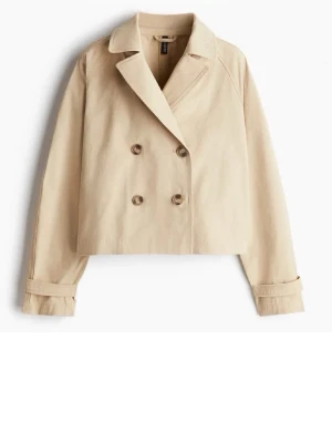 Kort beige trenchcoat från hm - Stilren kort trenchcoat i beige från HM med dubbelknäppning framtill, klassisk krage och snygga manschetter. Jackan har en boxig passform och dekorativ detalj med knapp baktill. Perfekt för lager-på-lager och trendig look.