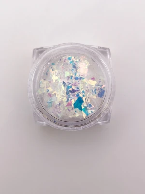 Iridescent nagelglitter flakes foil dichromate full - Säljer en ny burk med iriserande nagelglitter flakes i olika former och storlekar. Färgerna skiftar i vitt, blått, rosa och lila beroende på ljuset. Perfekt för att skapa unika och glittriga nageldesigner. Kommer i en genomskinlig plastburk.