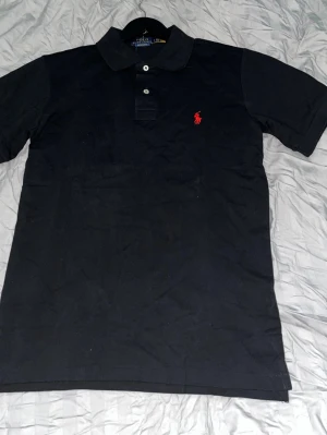 Svart polotröja från Polo Ralph Lauren - Klassisk svart polotopp från Polo Ralph Lauren, toppenskick. 🛑Skriv vid funderingar.                  🛑Snabb affär=kan gå ner i pris