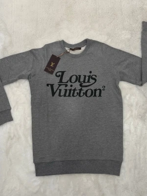 Grå sweatshirt från Louis Vuitton - Snygg grå sweatshirt från Louis Vuitton med svart logotyptryck på bröstet. 