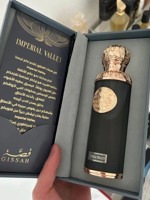 Imperial ever Valley parfym från Gissah - Lyxig parfymflaska från Gissah, modell Imperial Valley. Flaskan är mörkgrå med eleganta gulddetaljer och ett dekorativt mönster på både kork och flaska. Kommer i exklusiv presentförpackning med matchande design. Perfekt för dig som gillar exklusiva dofter och snygg design , 180ML/200ML kvar. 