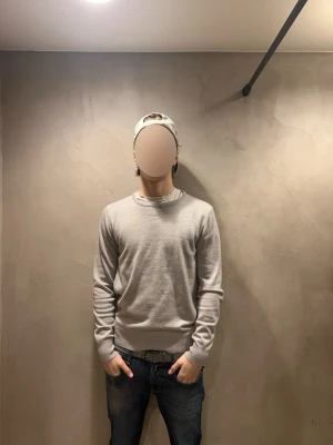 Ljusgrå basic tröja - En stilren ljusgrå tröja med rund halsringning och ribbade muddar vid ärmslut och nederkant. Tröjan har en enkel och clean design som passar till det mesta. Perfekt för dig som gillar en minimalistisk look.