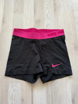 Nike Pro svarta träningsshorts - Snygga svarta träningsshort från Nike Pro med rosa bred resår. I storlek xs 💕