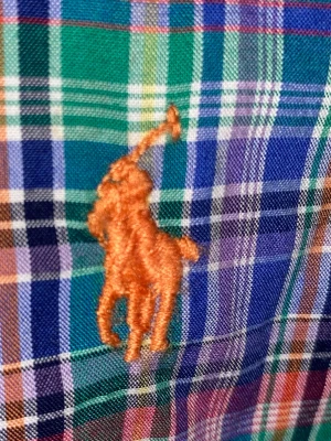 Rutig skjorta från Ralph Lauren - Klassisk rutig skjorta från Ralph Lauren med broderad logga på bröstet. Skjortan har en button-down krage, långa ärmar och knäppning framtill. Färgerna går i blått, grönt, rött och vitt. Perfekt för en avslappnad men ändå stilren look.