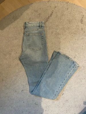 Ljusblå bootcut jeans  - Säljer ett par ljusblå bootcut jeans. Jeansen har hög midja och råa kanter längst ner. Tillverkade i denim med en avslappnad passform och subtila detaljer på fickorna.
