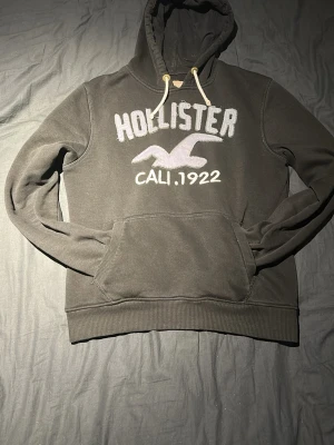 svart hoodie från Hollister - En svart hoodie från Hollister med turkos text. Otroligt snygg och stilren hoodie. XXL är storleken på tröjan men är krymt och passar en som är mellan 172-179 cm. Tyvärr lite för liten för mig som är 181 cm men passar perfekt för nån under 180 cm. Hoodien är i ett jätte fint skick och hör av er vid frågor, PRIS KAN DISKUTERAS!