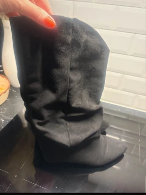 Svarta boots i mockaimitation - Svarta stövlar med lite lös passform.  I mockaimitation med låg klack (knappt någon klack alls). Perfekta för att lyfta en outfit med trendig och avslappnad stil. Lika de trendiga bootsen från Nelly💞knappt använda köpte från en annan på vinted så vet ej vart de är ifrån