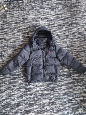 Äkta ralph lauren jacka - Ralh lauren jacka svart storlek M, äkta. Har små hål i armerna som gör att ibland kan det komma fjäder ut. Annars inget fel, har haft den bara en månad