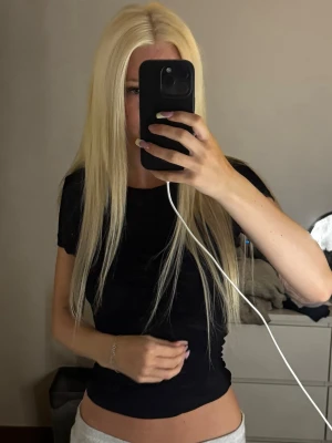 Svart croppad t-shirt - En enkel och stilren svart croppad t-shirt med korta ärmar. Perfekt för att matcha med jeans eller kjol och ger en snygg och avslappnad look. Materialet känns mjukt och stretchigt, vilket gör den bekväm att bära.