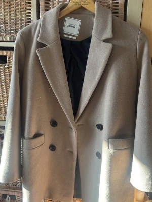 Beige kavaj från Pimkie - Stilren beige ull  kavaj från Pimkie med dubbelknäppning och svarta knappar. Klassisk krage, två fickor framtill och helsvart foder. Perfekt för en trendig och snygg look.🫶🏼🩷