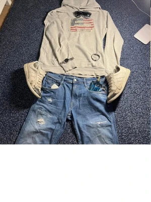 Blå slitna jeans från Replay - Säljer ett par blå jeans från Replay med slitna detaljer och klassisk femficksmodell. Jeansen är tillverkade i bomullsmix från deras Sustainable Lab-kollektion. Perfekta för en casual och trendig look. Storlek 32/32. Priset går att diskutera. Va inte rädda att skriva!