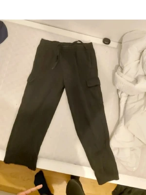 Svarta cargobyxor - Snygga svarta cargobyxor med klassiska cargofickor på sidorna. Byxorna har en avslappnad passform och är perfekta för en streetwear-look. Materialet ser ut att vara mjukt och bekvämt.