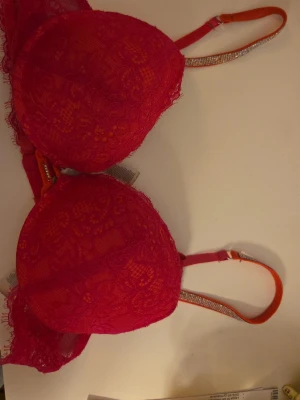 Rosa spets-bh med push-up - Snygg rosa bh med push-up och vadderade kupor. Utsidan är täckt av spets med blommönster och axelbanden är dekorerade med glittriga detaljer. Insidan är mjuk för extra komfort. Perfekt för dig som vill ha något både bekvämt och stilrent. Säljer en likadan i vit. Priset kan diskutera!